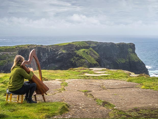 Ireland, woman playing a harp near the sea – mobile Ireland, woman playing a harp near the sea
