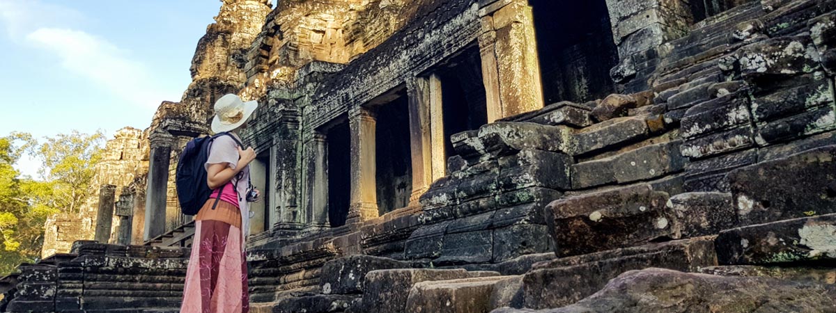lady tourist with backpack examining the ruins of Angkor Wat